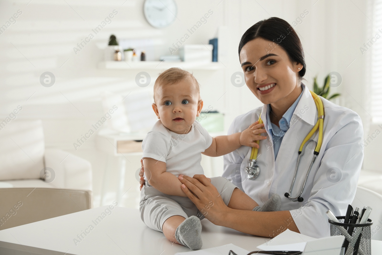 Photo of Young pediatrician examining cute little baby in clinic