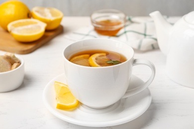 Photo of Hot tea with mint and lemon on white table