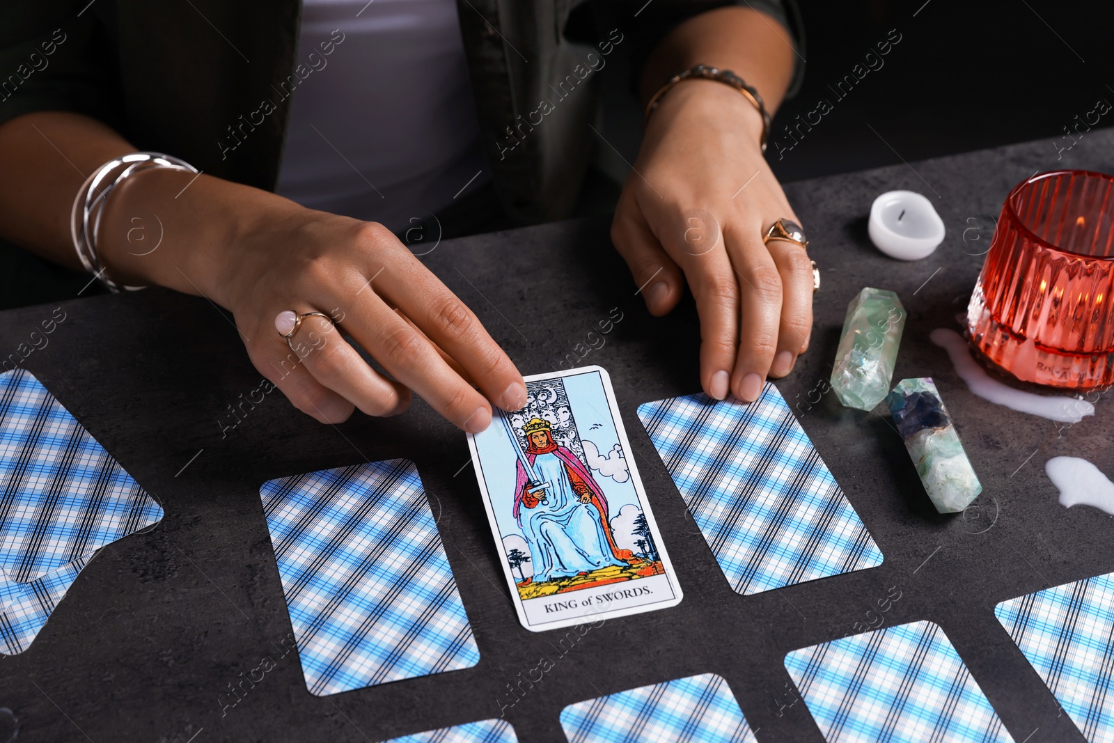 Photo of Fortune teller predicting future on spread of tarot cards at grey table, closeup