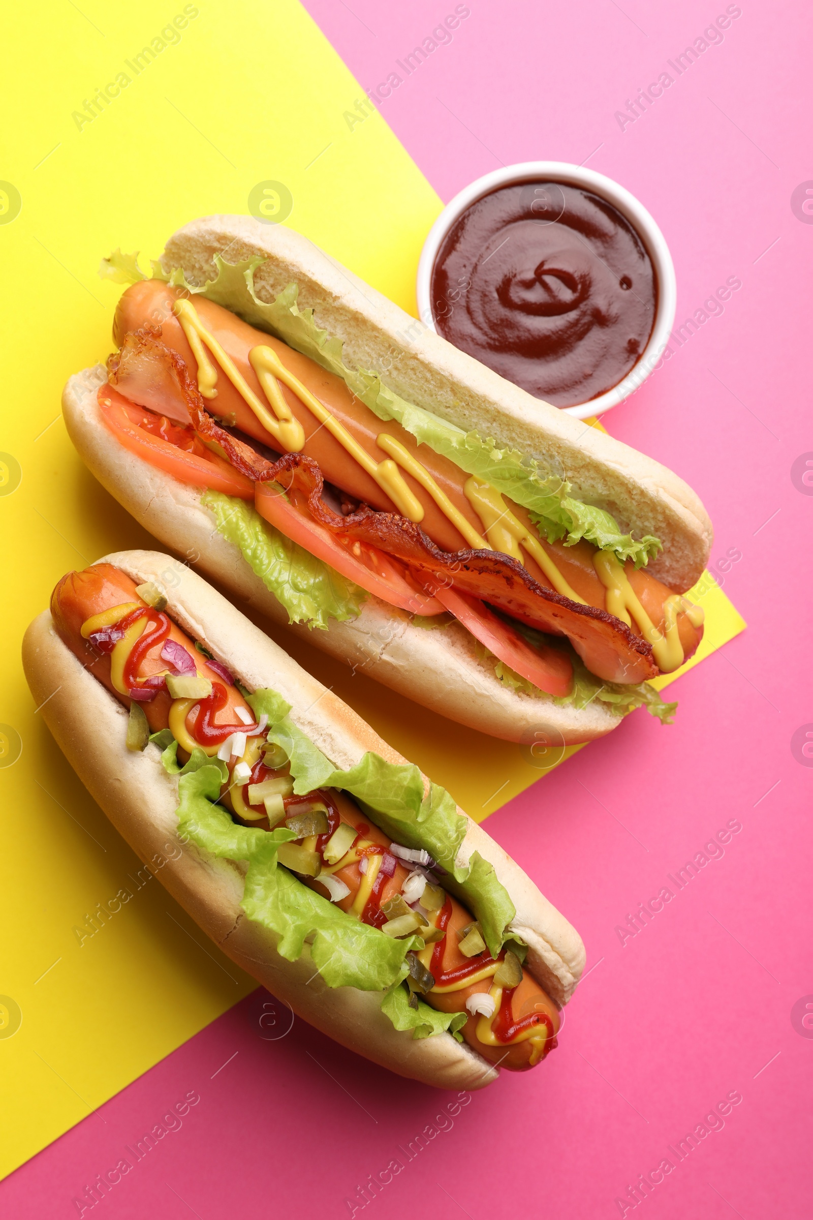 Photo of Delicious hot dogs with lettuce and sauces on color background, flat lay