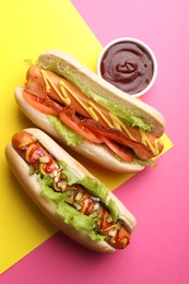 Photo of Delicious hot dogs with lettuce and sauces on color background, flat lay