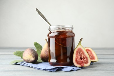 Photo of Jar of tasty sweet jam and fresh figs on grey table