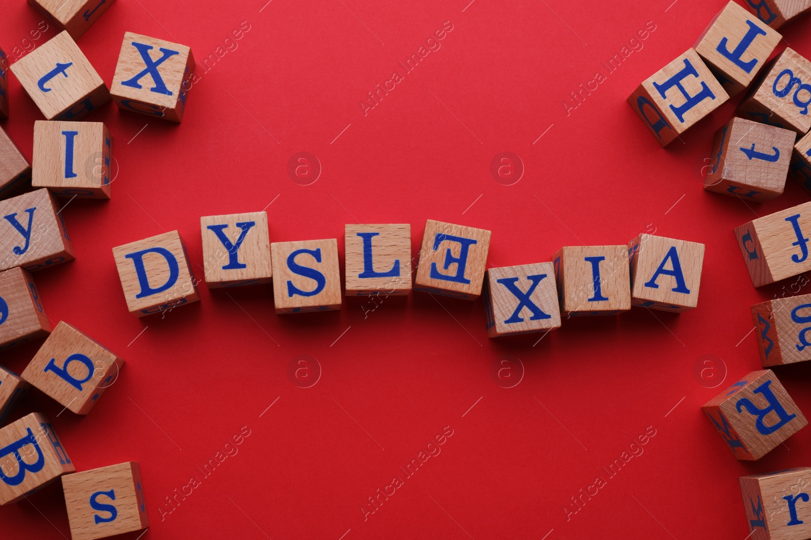 Photo of Word Dyslexia with inverted letter E of wooden cubes on red background, flat lay