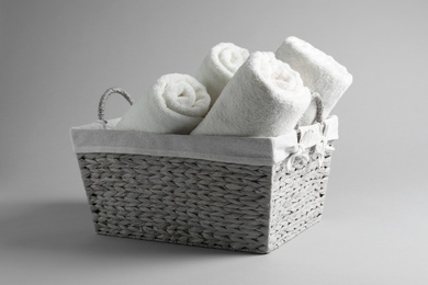 Photo of Basket with rolled towels on light background