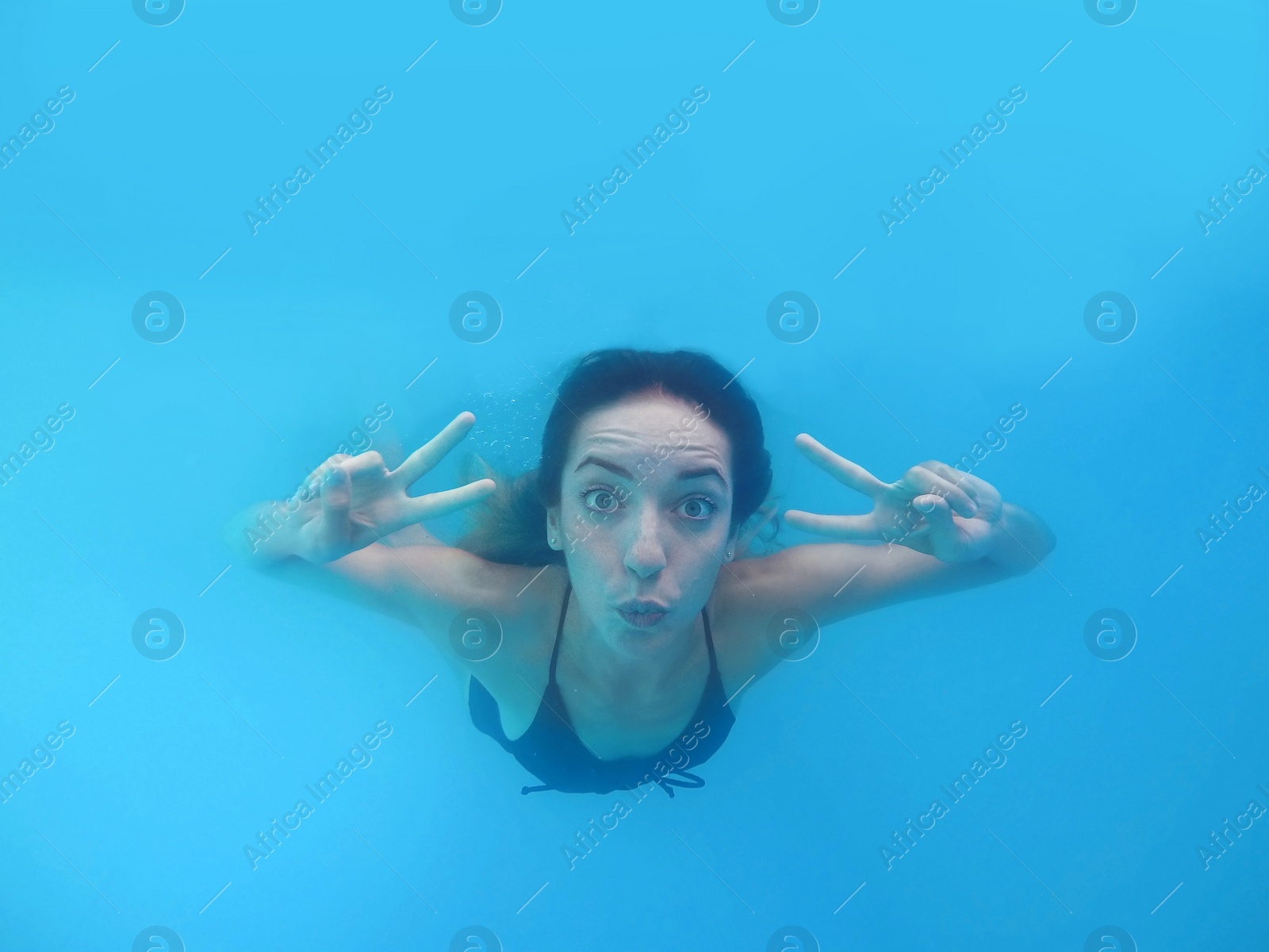 Photo of Beautiful young woman swimming in pool, underwater view