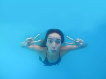 Beautiful young woman swimming in pool, underwater view