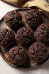 Photo of Board with delicious chocolate muffins on light table, top view