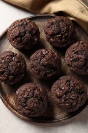 Board with delicious chocolate muffins on light table, top view