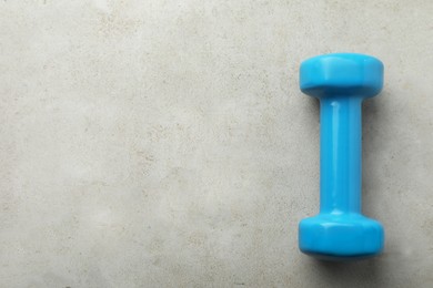 Photo of One light blue dumbbell on light grey table, top view. Space for text