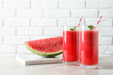 Tasty summer watermelon drink in glasses and board with sliced fruit on table