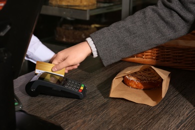 Woman with credit card using payment terminal at shop, closeup