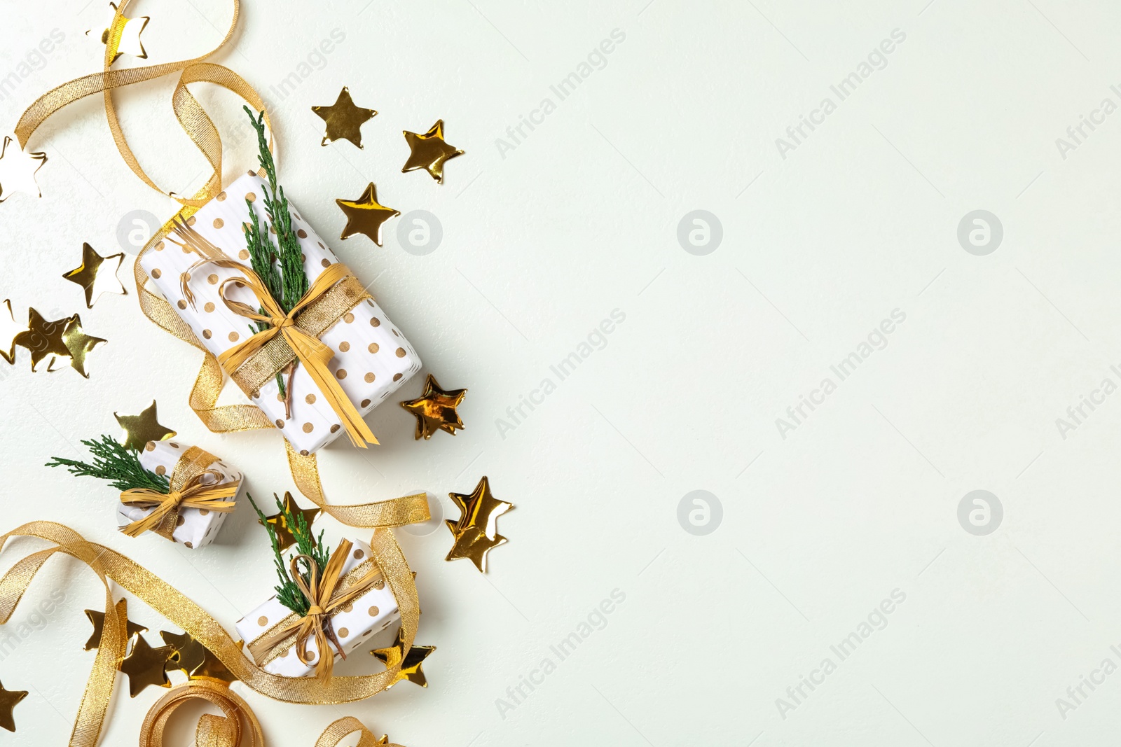 Photo of Christmas gift boxes with golden ribbon on white background, flat lay. Space for text