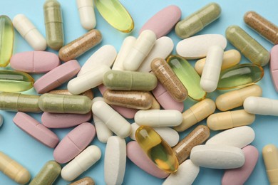 Photo of Different vitamin pills on light blue background, flat lay