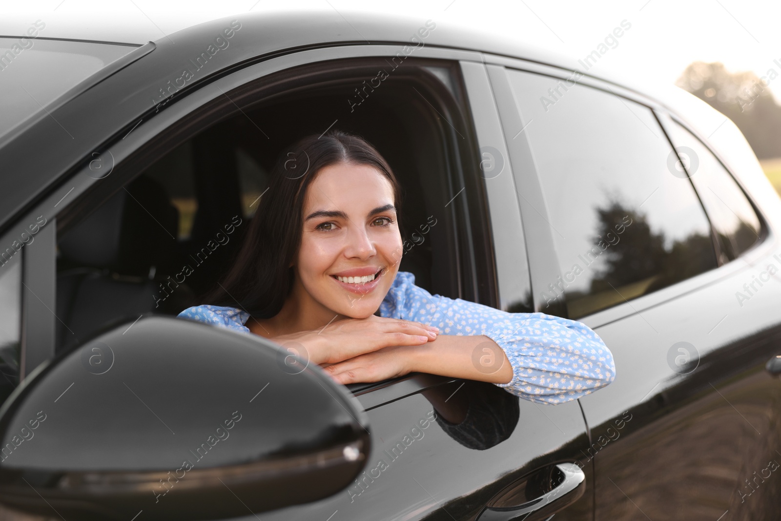 Photo of Enjoying trip. Portrait of beautiful happy woman in car, view from outside