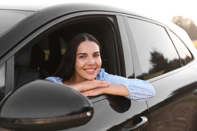 Photo of Enjoying trip. Portraitbeautiful happy woman in car, view from outside