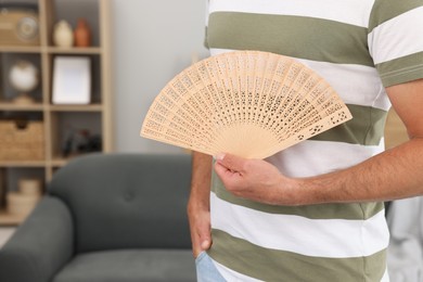 Photo of Man with hand fan at home, closeup