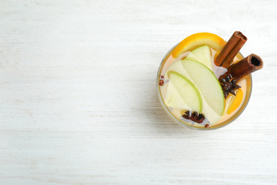 Photo of Aromatic white mulled wine on wooden table, top view. Space for text