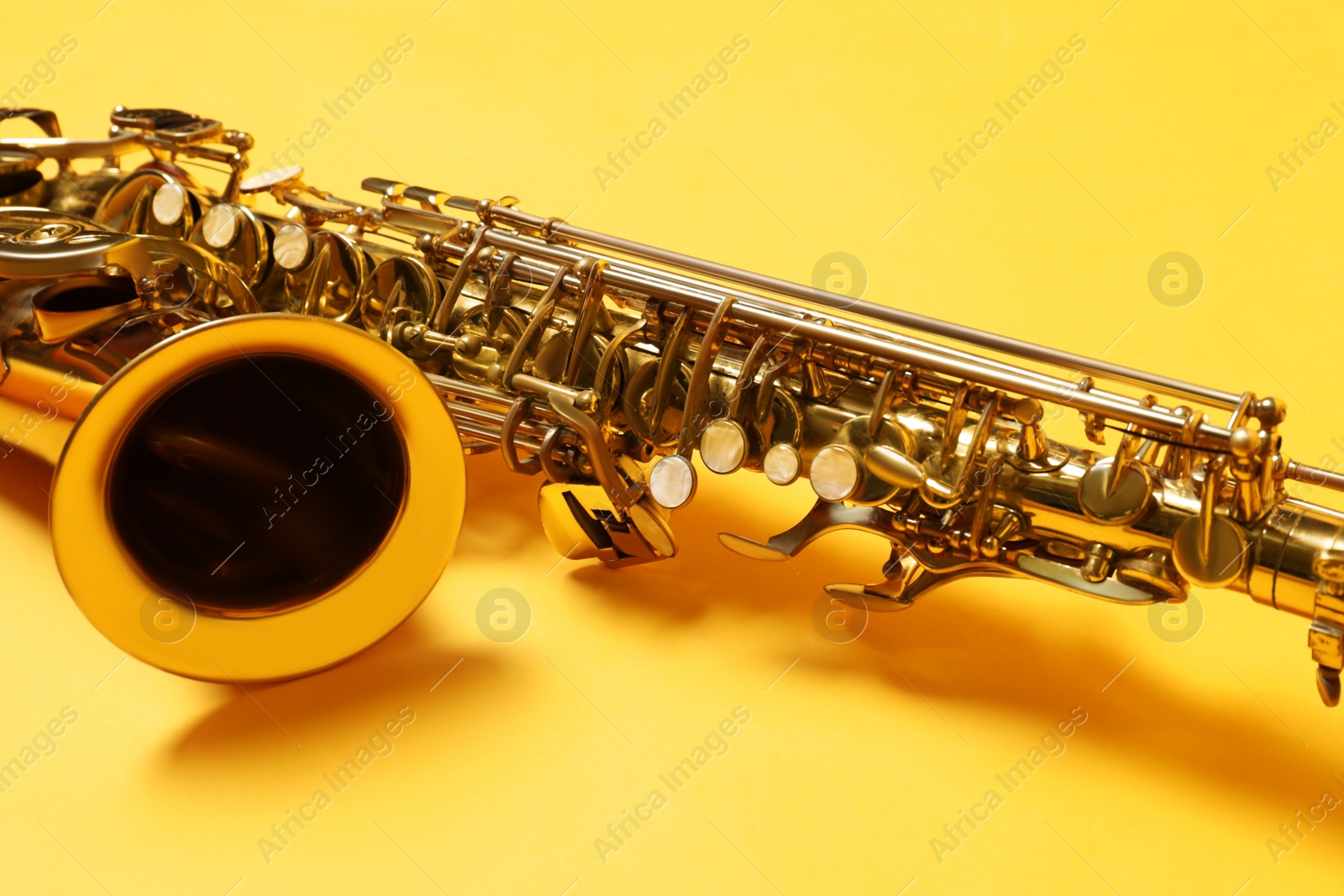 Photo of Beautiful saxophone on yellow background, closeup view
