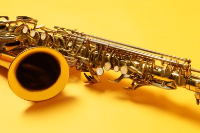 Beautiful saxophone on yellow background, closeup view