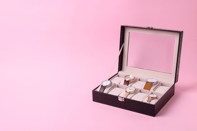 Photo of Black jewelry box with different wristwatches on pink background. Space for text