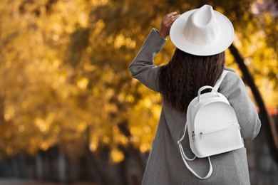 Young woman with stylish white backpack on city street, back view. Space for text