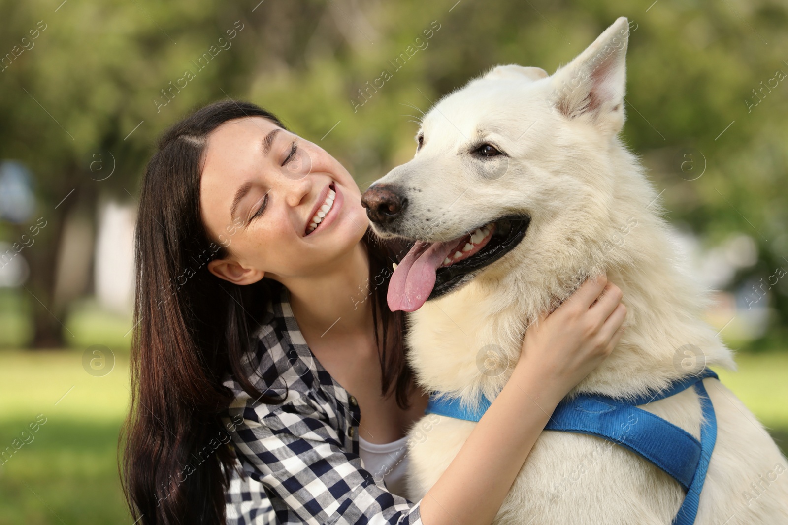 Photo of Teenage girl hugging her white Swiss Shepherd dog in park