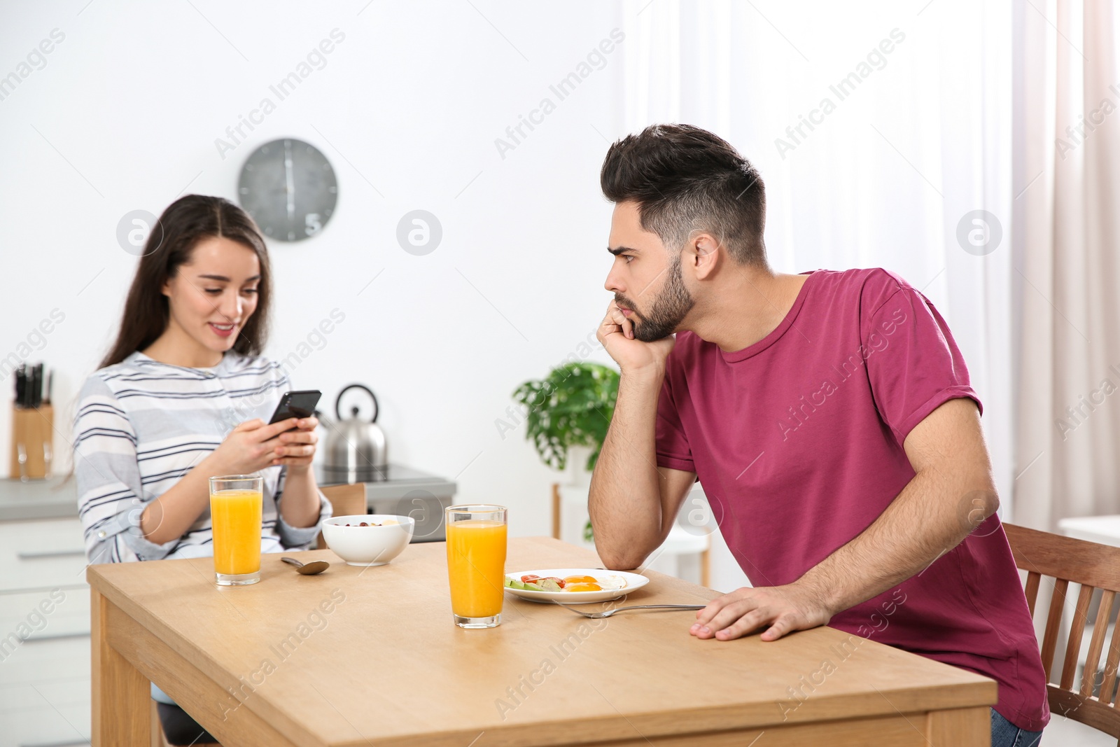 Photo of Young woman preferring smartphone over her boyfriend at home