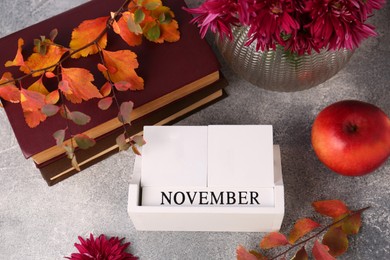 Photo of Thanksgiving day, holiday celebrated every fourth Thursday in November. Flat lay composition with wooden block calendar and autumn leaves on grey table