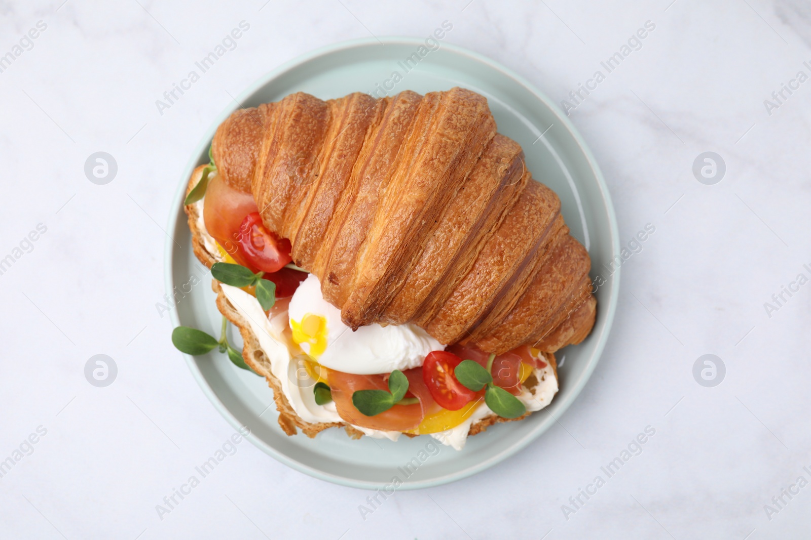 Photo of Tasty croissant with fried egg, tomato and microgreens on white table, top view