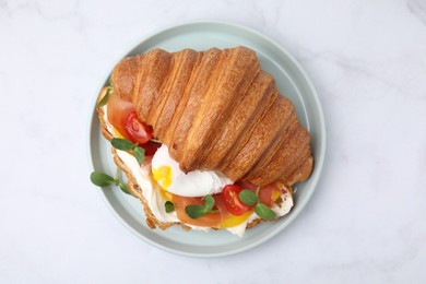 Photo of Tasty croissant with fried egg, tomato and microgreens on white table, top view
