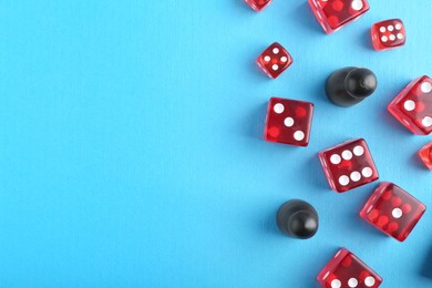 Photo of Many red dices and color game pieces on light blue background, flat lay. Space for text