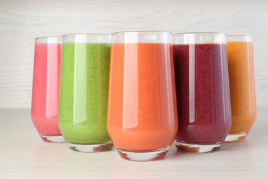 Photo of Fresh colorful fruit smoothies on white wooden table, closeup