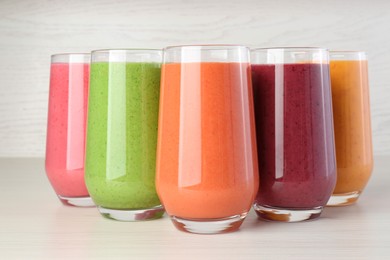 Fresh colorful fruit smoothies on white wooden table, closeup