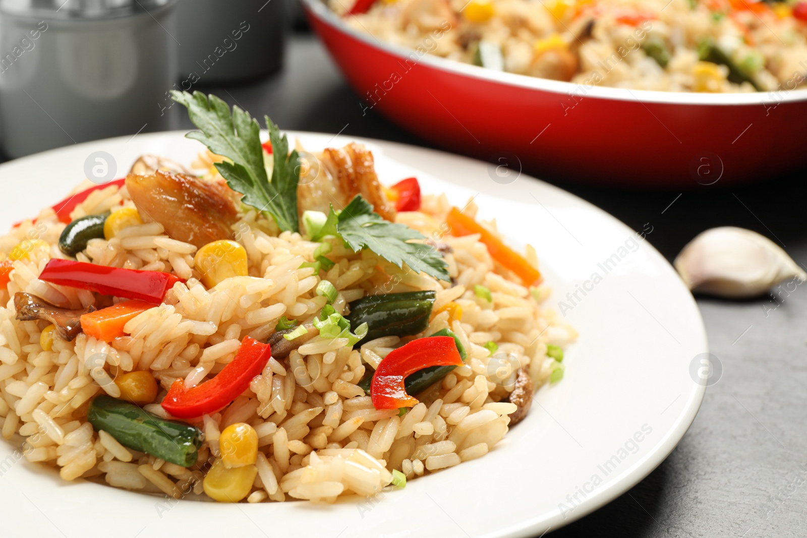 Photo of Delicious rice pilaf with chicken and vegetables on black table, closeup