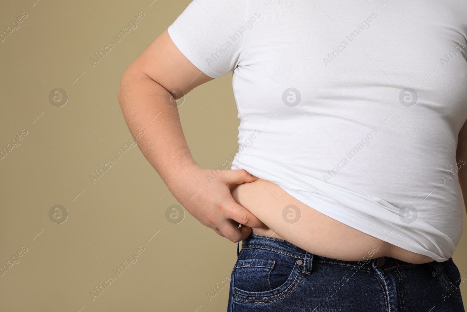 Photo of Overweight man in tight t-shirt on beige background, closeup