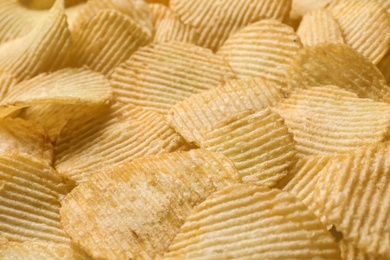 Photo of Pile of crispy potato chips as background, closeup