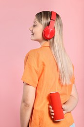 Beautiful happy woman holding red beverage can on pink background