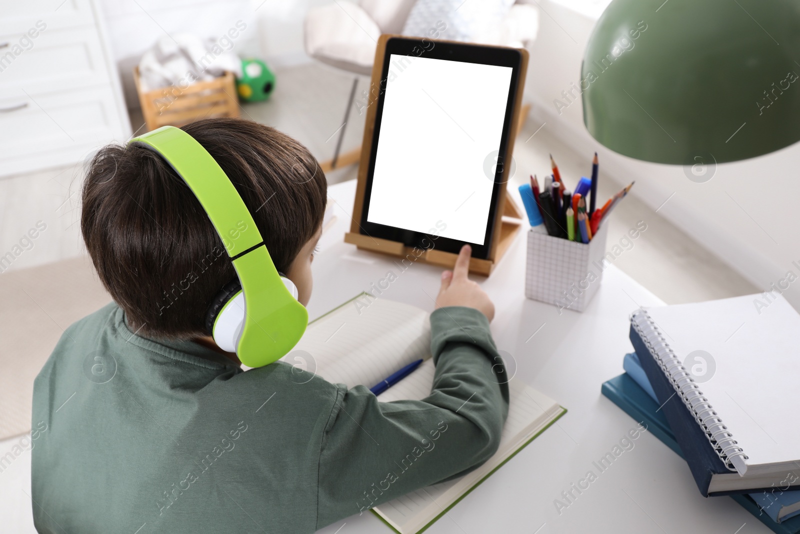 Photo of Cute little boy with modern tablet studying online at home. E-learning