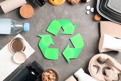 Recycling symbol and different garbage on gray background, top view