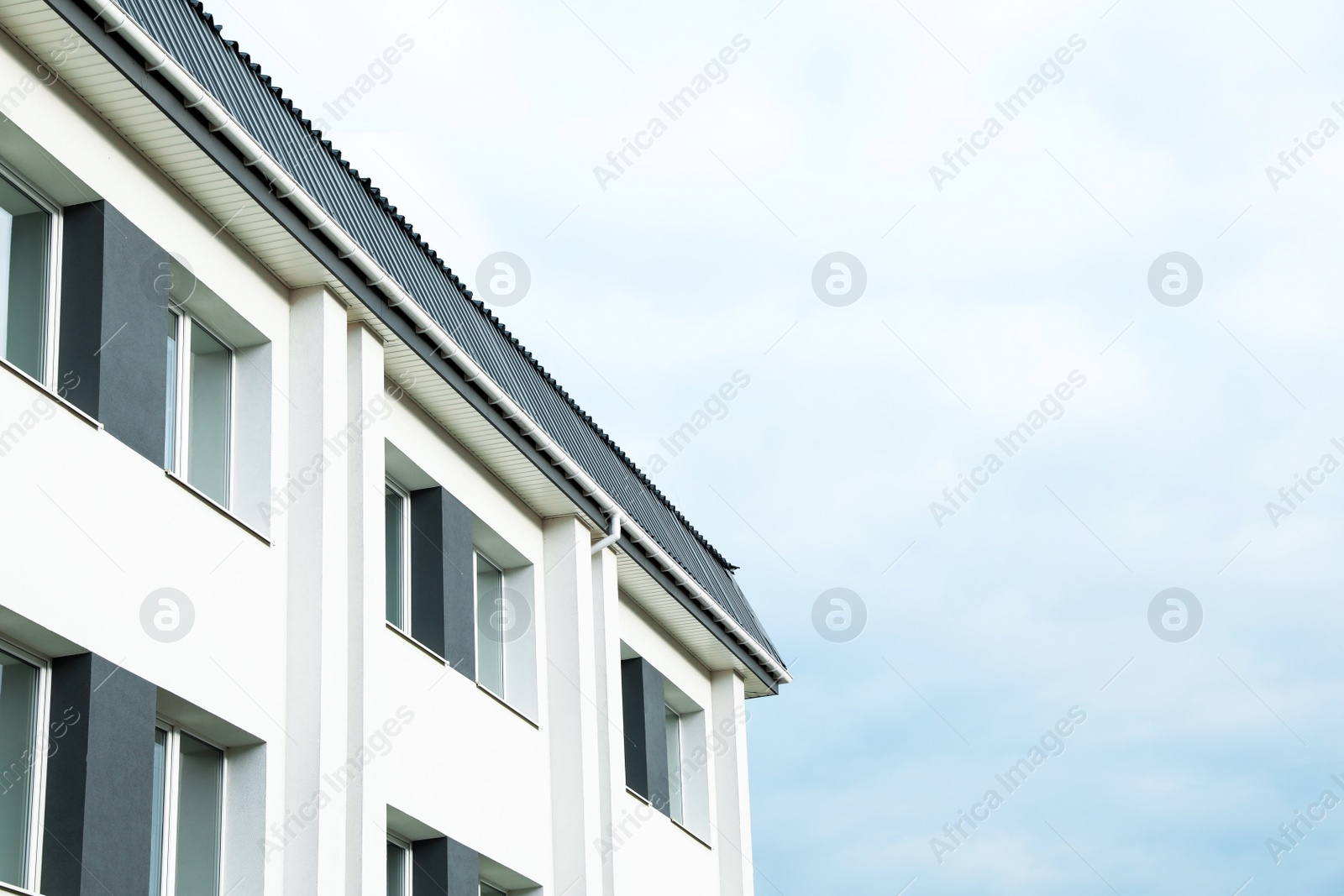 Photo of Exterior of white apartment building on cloudy day, low angle view. Space for text