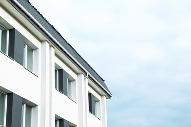 Exterior of white apartment building on cloudy day, low angle view. Space for text