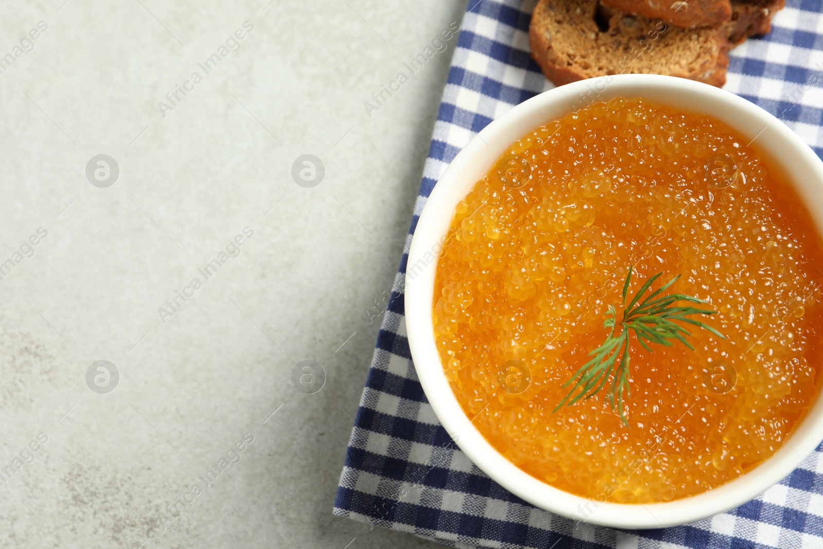 Photo of Fresh pike caviar in bowl and bread on light grey table, top view. Space for text