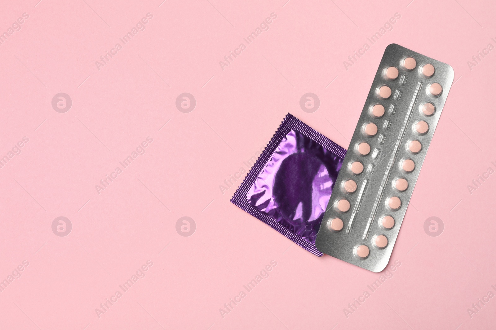 Photo of Condom and birth control pills on pink background, top view with space for text. Safe sex