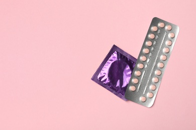 Photo of Condom and birth control pills on pink background, top view with space for text. Safe sex