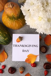 Photo of Thanksgiving day, holiday celebrated every fourth Thursday in November. Flat lay with paper card and autumn leaves on grey table