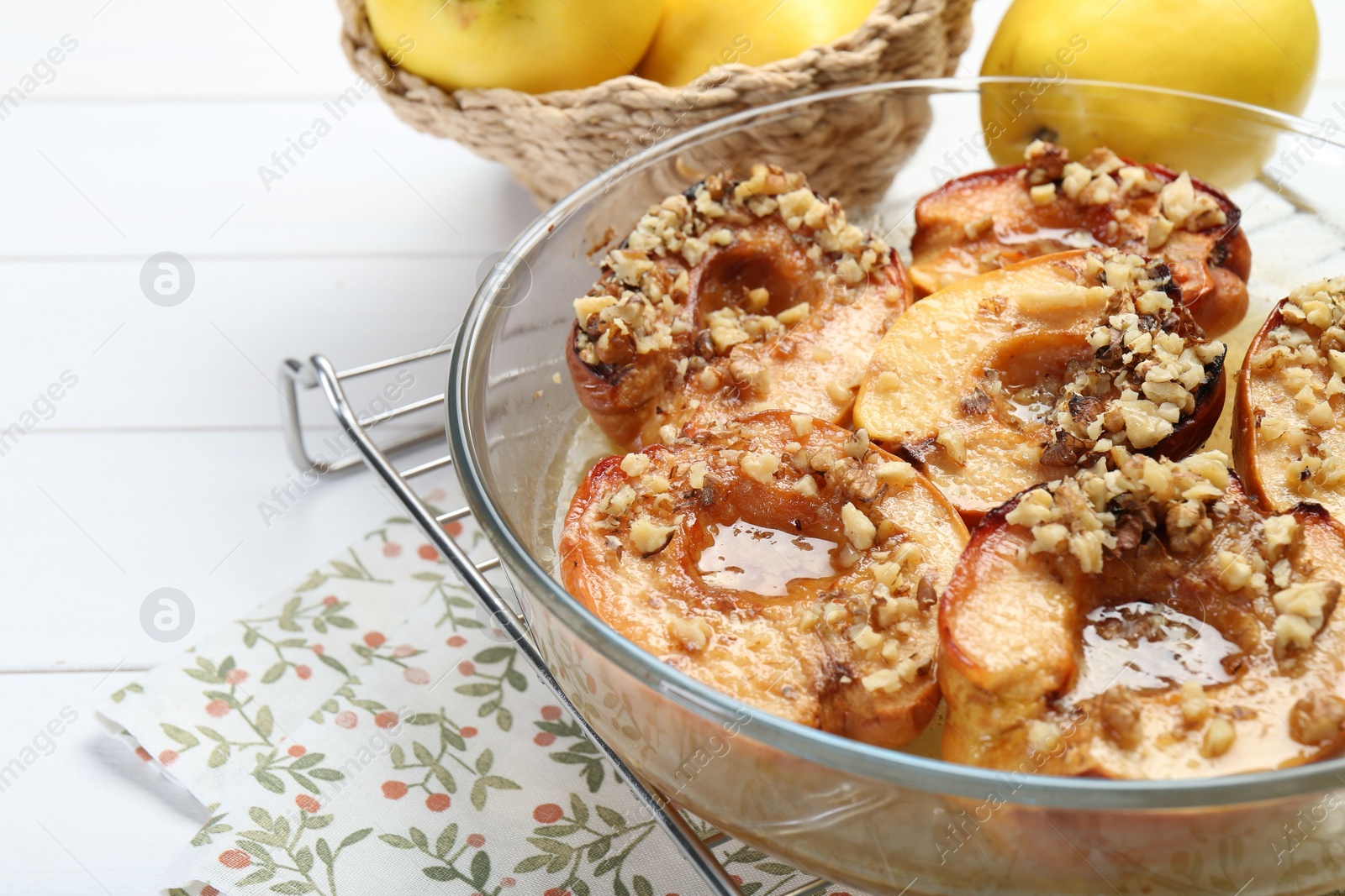 Photo of Delicious baked quinces with nuts in bowl and fresh fruits on white wooden table, closeup