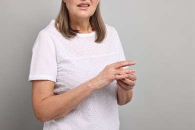 Arthritis symptoms. Woman suffering from pain in fingers on gray background, closeup