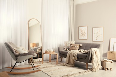 Photo of Stylish living room interior with large mirror, comfortable sofa and rocking chair