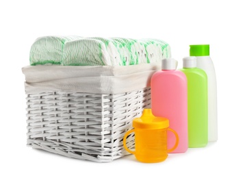 Photo of Basket with diapers and baby accessories on white background