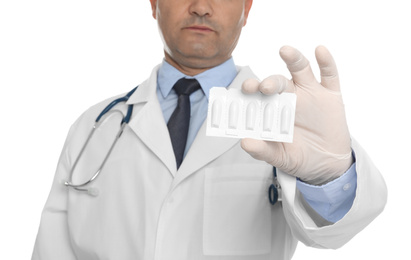 Photo of Doctor holding suppositories for hemorrhoid treatment on white background, closeup